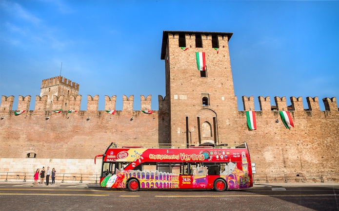 Verona sightseeing bus in front of Castelvecchio on a sunny day.