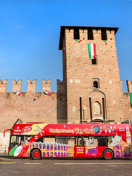 Verona sightseeing bus in front of Castelvecchio on a sunny day.