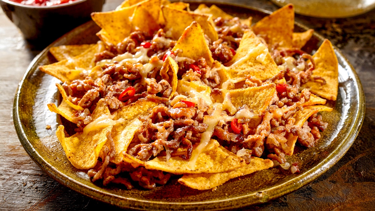Plate of nachos topped with ground beef, cheese, and jalapeños.
