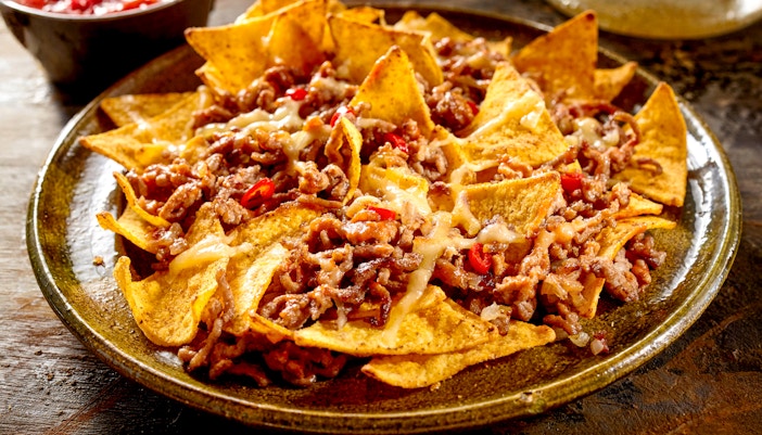 Plate of nachos topped with ground beef, cheese, and jalapeños.