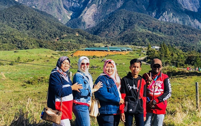 Group of tourists at Mount Kinabalu with scenic view of Kundasang in the background.