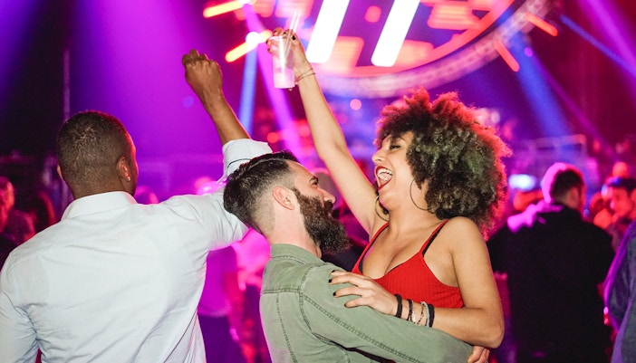 People dancing at a vibrant Amsterdam Dance Event (ADE) with colorful lights and energetic atmosphere.