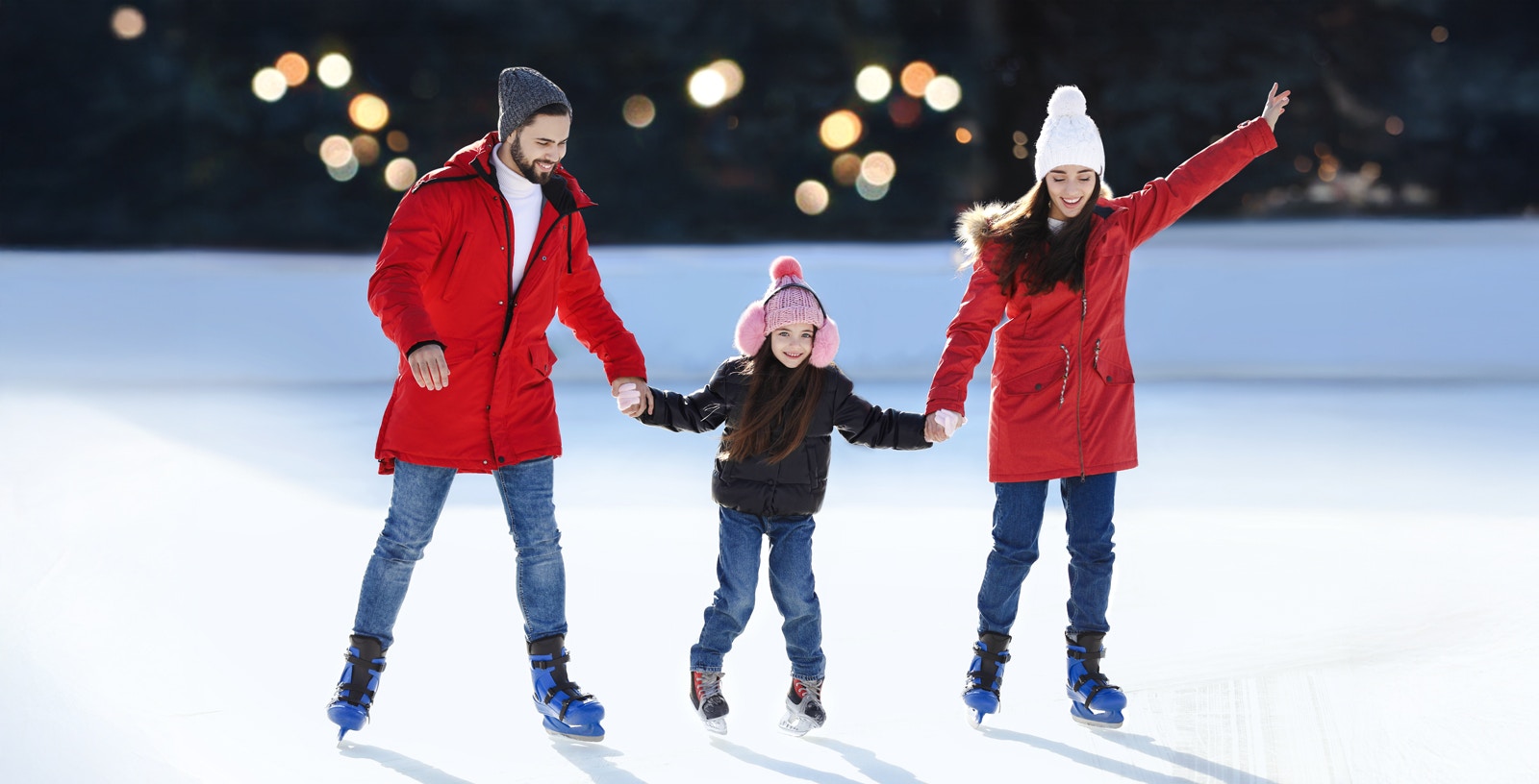 Family ice skating together at an outdoor rink.