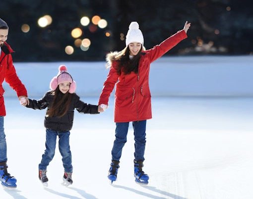 Family ice skating together at an outdoor rink.