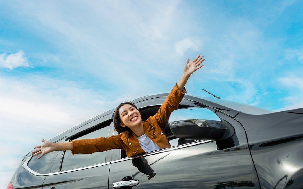 Person enjoying a car ride with arms out, representing KLIA/KLIA2 private transfer to Kuala Lumpur.