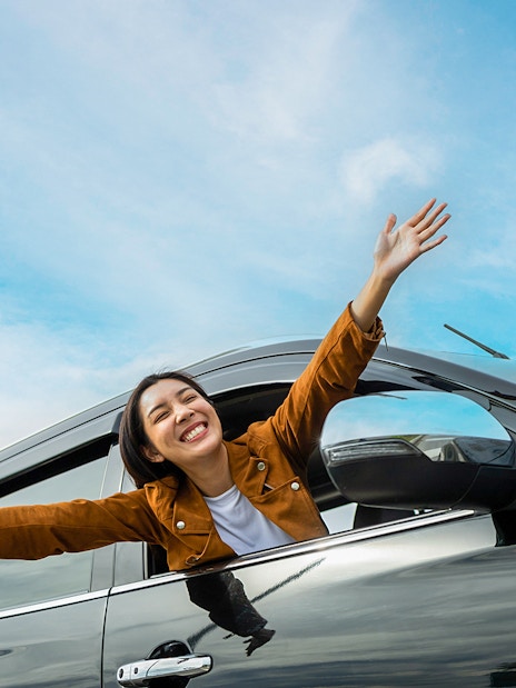 Person enjoying a car ride with arms out, representing KLIA/KLIA2 private transfer to Kuala Lumpur.