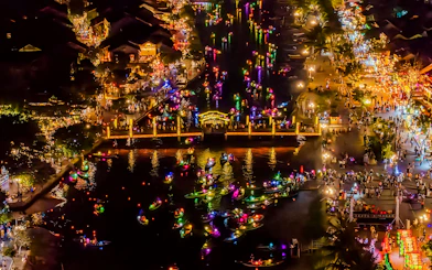 Hoi An river at night with colorful lanterns and boats, bustling with people.