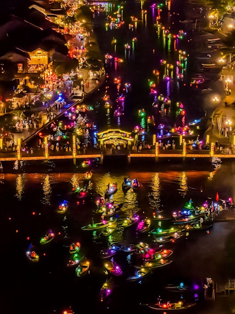 Hoi An river at night with colorful lanterns and boats, bustling with people.