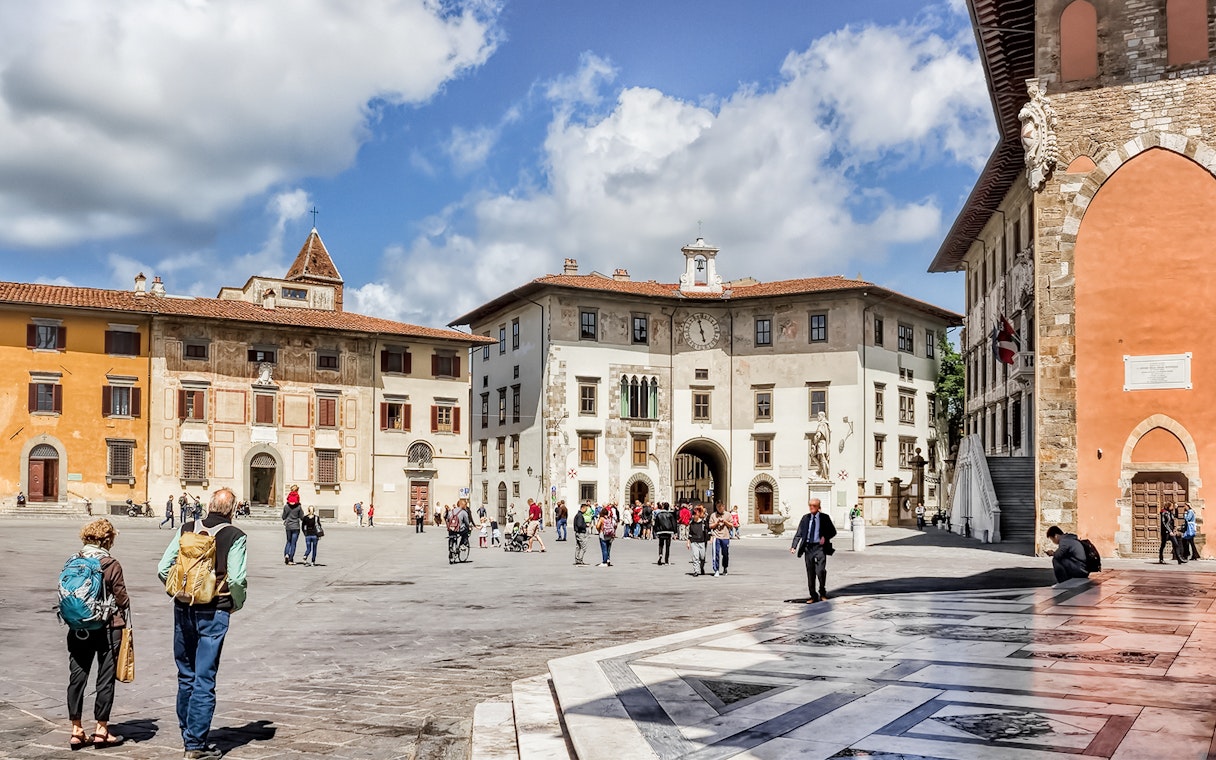 Piazza dei Cavalieri in Pisa with tourists exploring historic buildings.