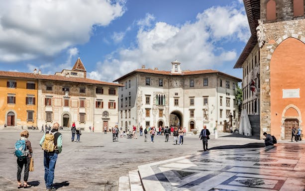 Piazza dei Cavalieri in Pisa with tourists exploring historic buildings.
