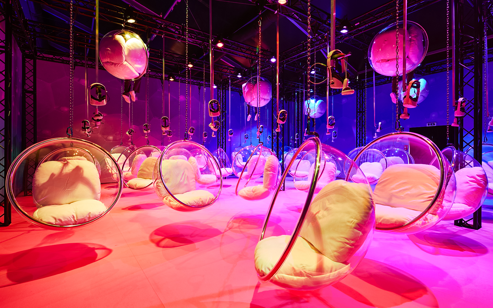 Hanging bubble chairs with cushions in a colorful room at Bubble Planet, Washington DC.