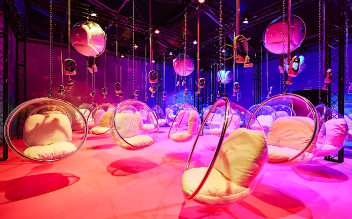 Hanging bubble chairs with cushions in a colorful room at Bubble Planet, Washington DC.