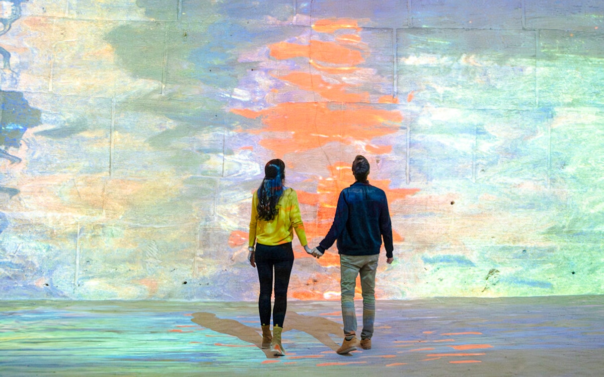 Couple viewing Monet projection at Carrières des Lumières, France.