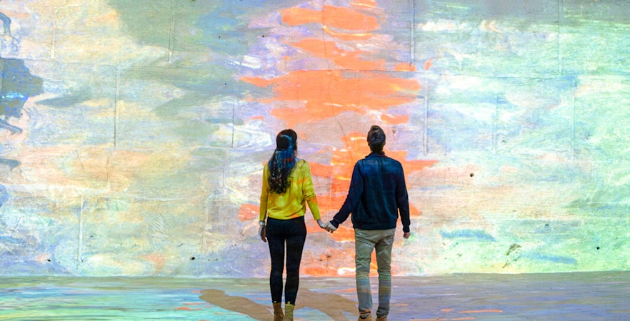 Couple viewing Monet projection at Carrières des Lumières, France.