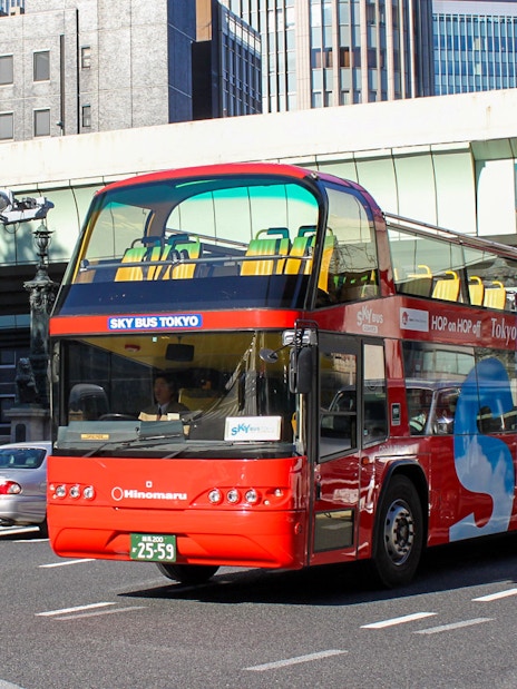 Tokyo hop-on hop-off red double-decker bus on city street.