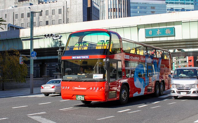 Tokyo hop-on hop-off red double-decker bus on city street.