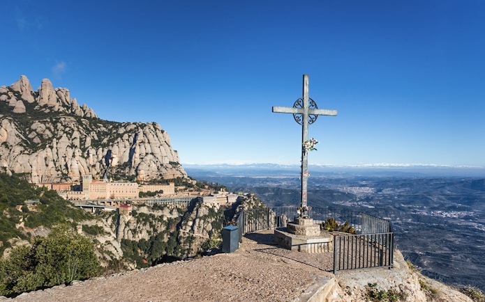 Cruz de San Miguel overlooking Montserrat Monastery and mountain landscape.