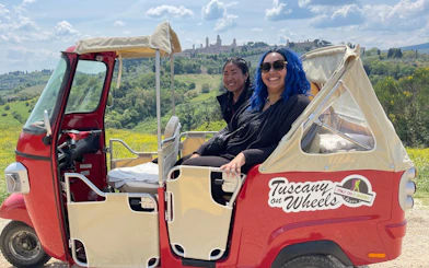 Tuk Tuk tour with local guide in Chianti Hills, San Gimignano skyline in background.