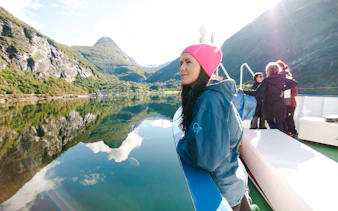 Geiranger fjord cruise with passengers enjoying scenic mountain views.