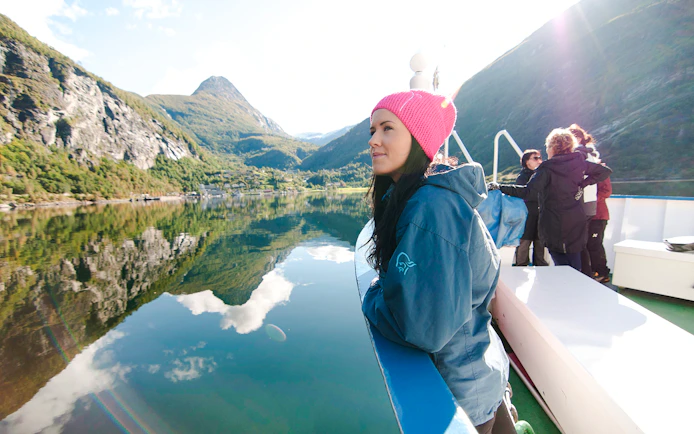 Geiranger fjord cruise with passengers enjoying scenic mountain views.