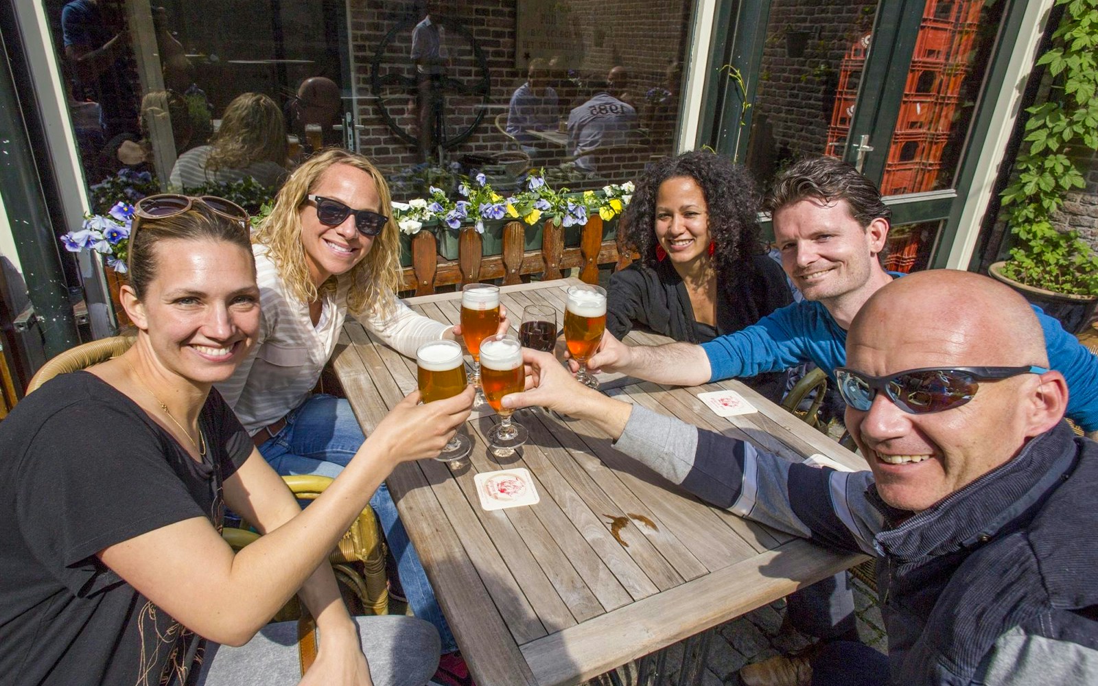 Guests enjoying beer on a Rotterdam boat tour with city skyline in the background.