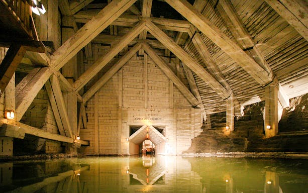 Wieliczka Salt Mine chamber with wooden beams and reflective water surface.