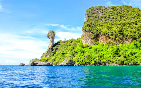 Rocky island with lush greenery in Krabi, viewed from the sea, part of 4 Islands tour.