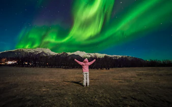 Tourist admiring Northern Lights in Reykjavik, Iceland.