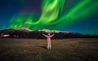 Tourist admiring Northern Lights in Reykjavik, Iceland.