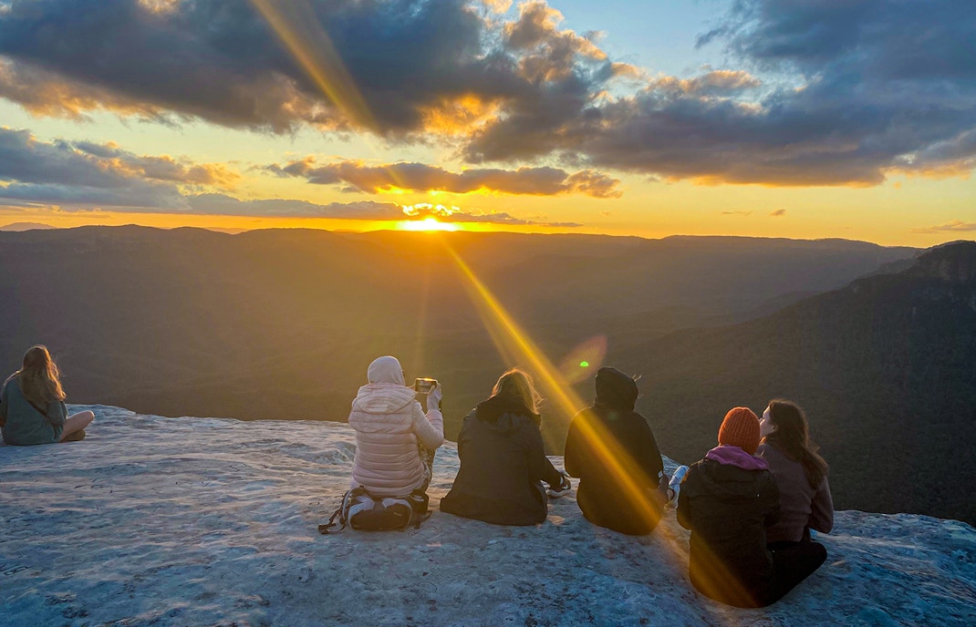 Tourists taking in the views of Jamison Valley at sunset on the Blue Mountains Sunset & Wilderness Day Trip from Sydney