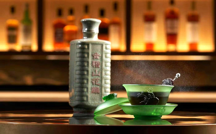 Cocktail in green frosted tea cup with saucer beside ceramic bottle at Resorts World Sentosa Singapore bar.