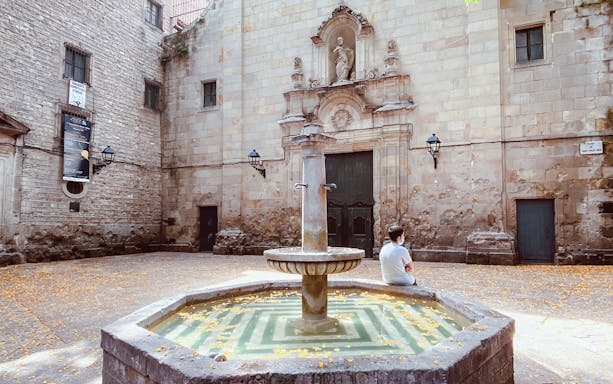 Barcelona Gothic Quarter courtyard with historic fountain and stone facade.