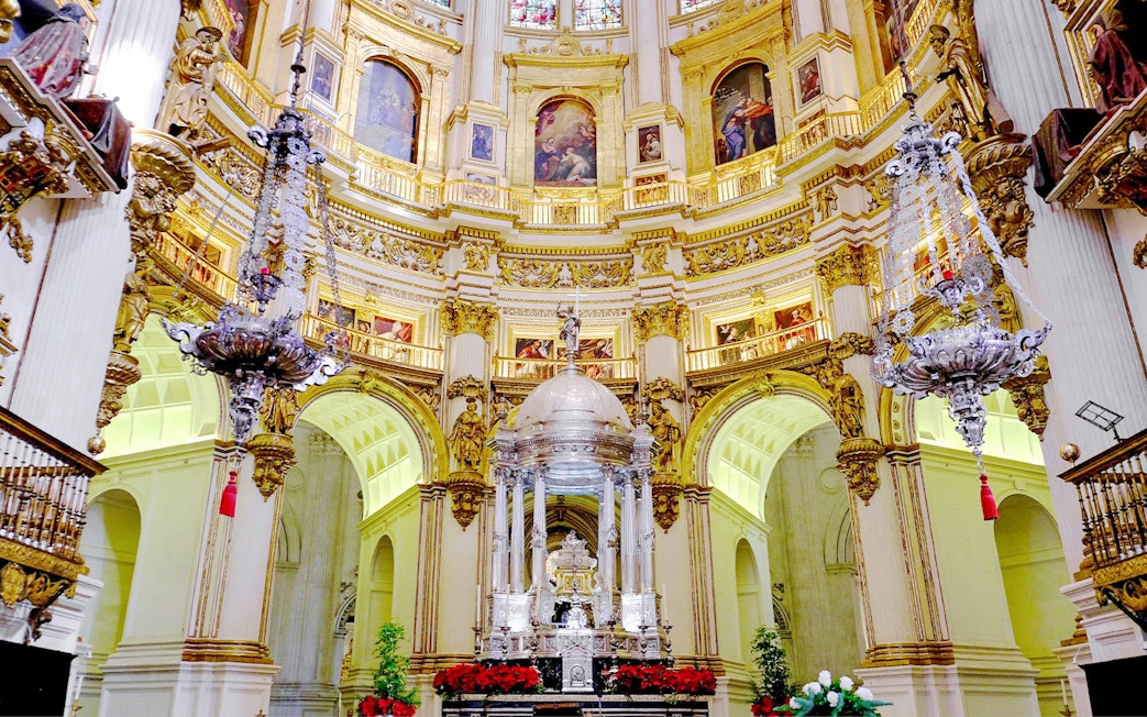 Interiors of the Cathedral and Royal Chapel of Granada with ornate altar and chandeliers.