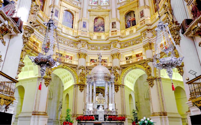 Interiors of the Cathedral and Royal Chapel of Granada with ornate altar and chandeliers.