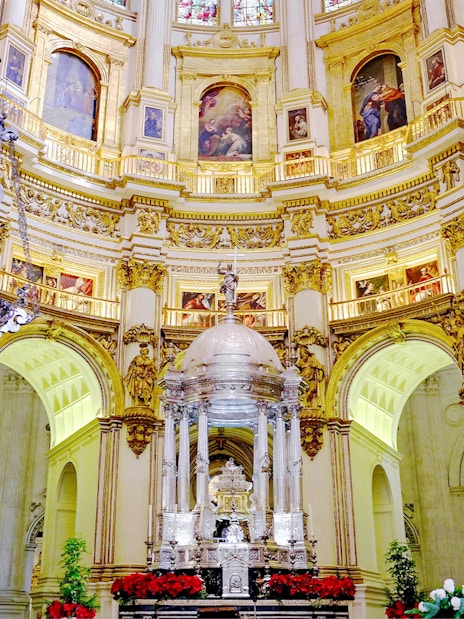 Interiors of the Cathedral and Royal Chapel of Granada with ornate altar and chandeliers.