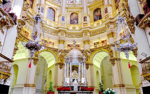 Interiors of the Cathedral and Royal Chapel of Granada with ornate altar and chandeliers.
