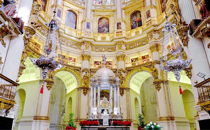 Interiors of the Cathedral and Royal Chapel of Granada with ornate altar and chandeliers.