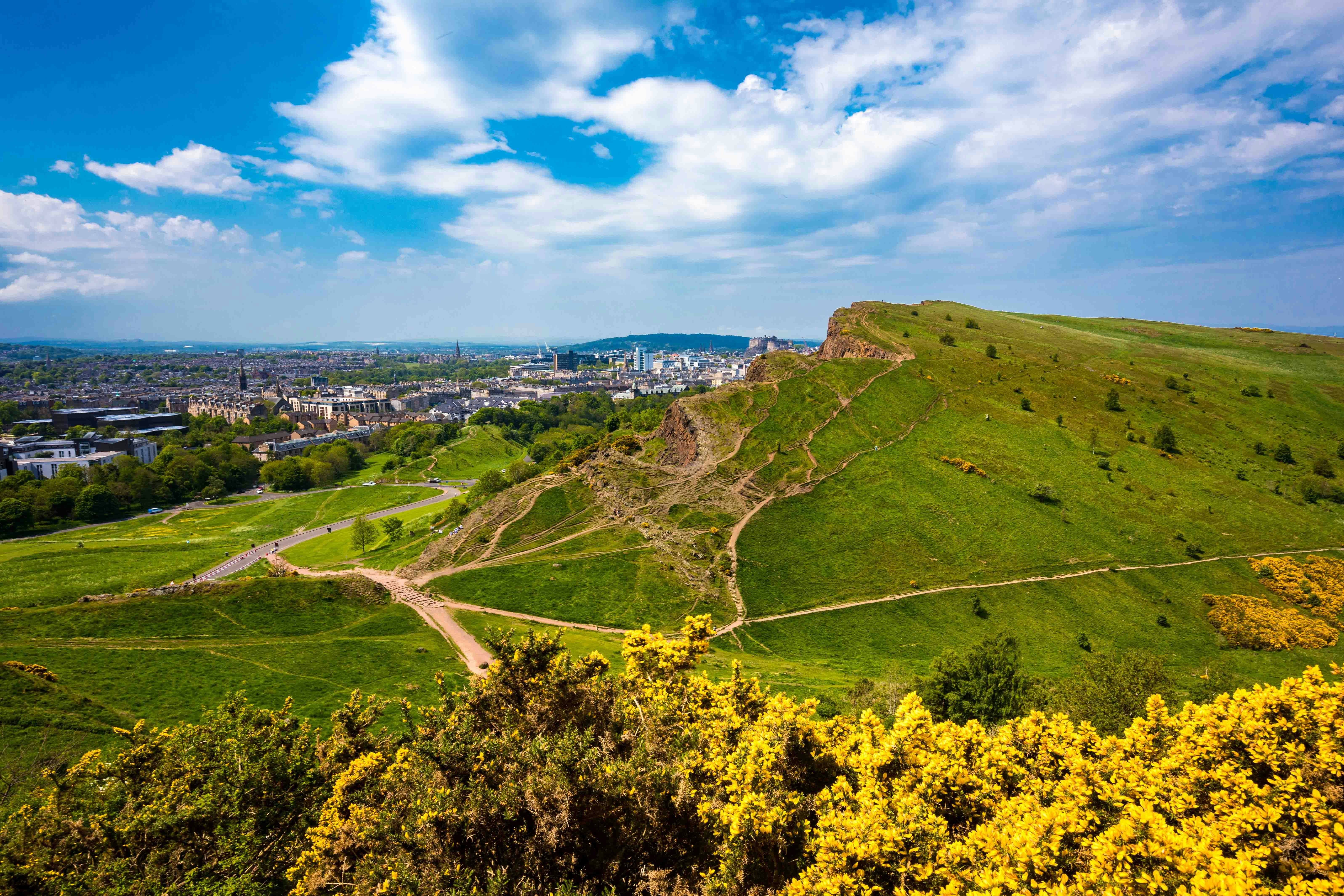 Arthur’s Seat overlooking Edinburgh cityscape with green hills and walking paths.