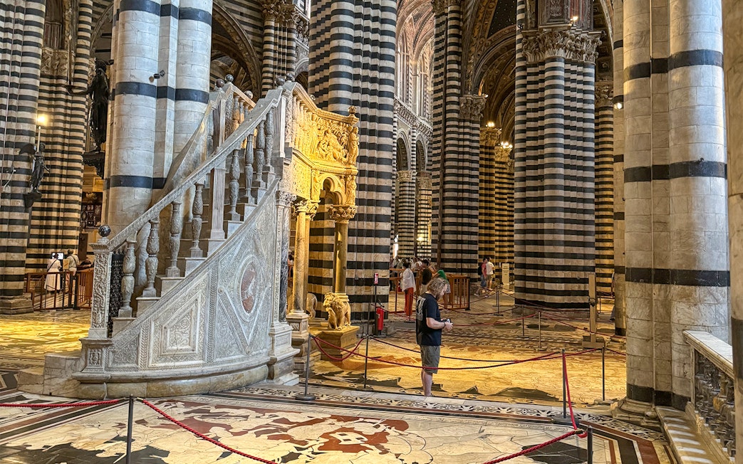 Siena Cathedral interior with striped columns and ornate staircase, Italy.