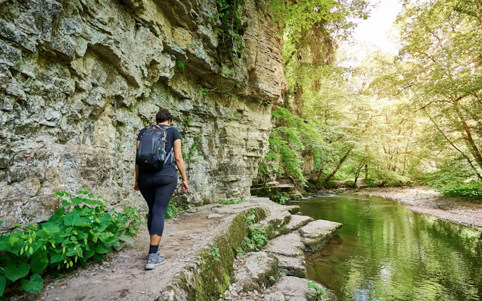 Person hiking along a rocky path beside a stream in the Black Forest, Germany.
