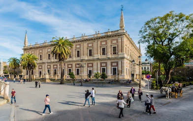 Seville's Archivo de Indias with tourists and horse-drawn carriage in the foreground.