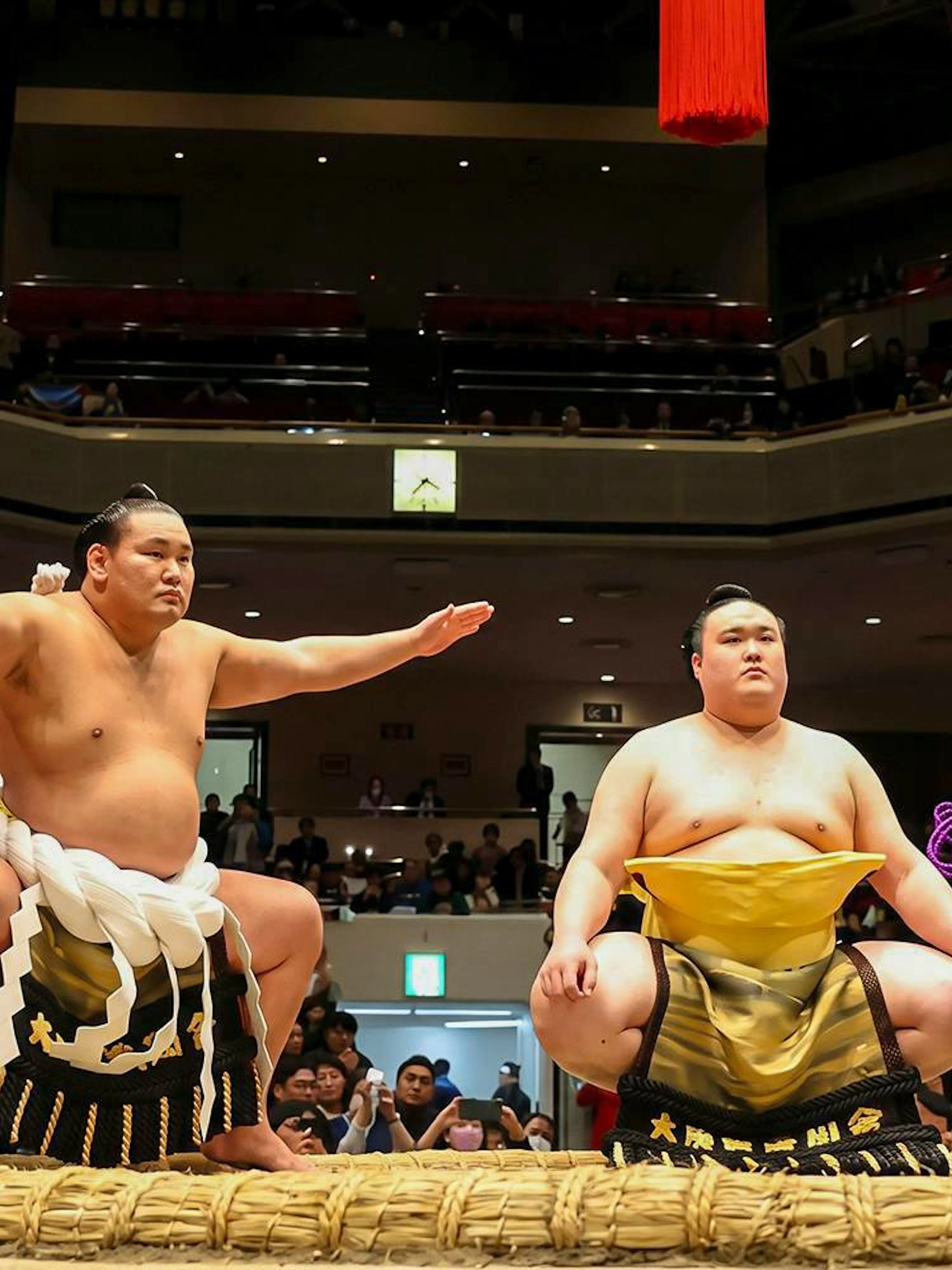 Sumo wrestlers and referee in traditional attire at Grand Sumo Tournament, Japan.