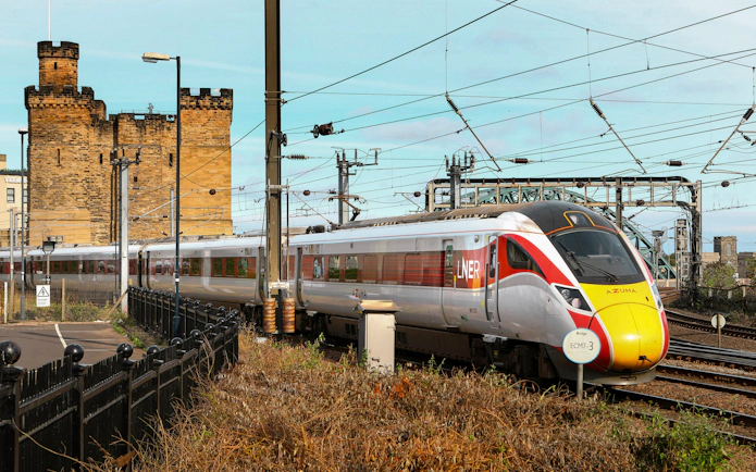 Train on BritRail network passing a historic castle in England.