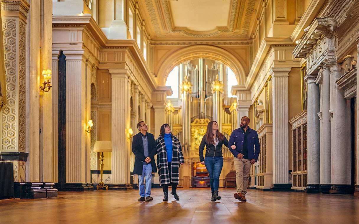 Visitors exploring the ornate Blenheim Palace State Rooms with grand columns and chandeliers.