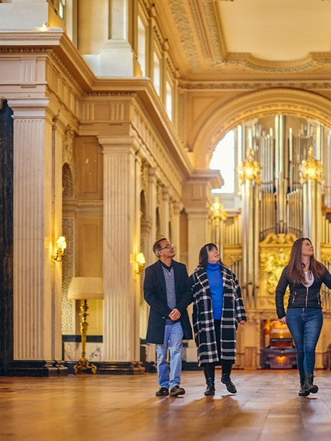 Visitors exploring the ornate Blenheim Palace State Rooms with grand columns and chandeliers.