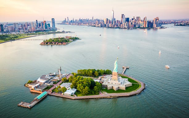 Statue of Liberty aerial view with Manhattan skyline in the background.