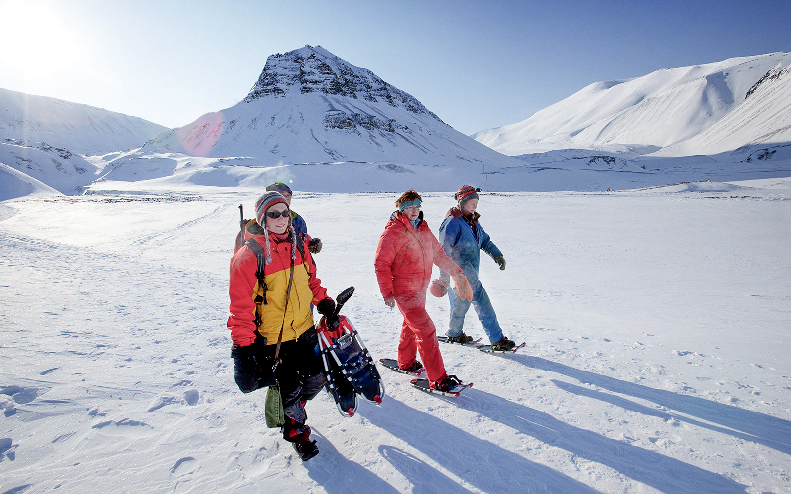 Group snowshoeing in snowy landscape, exploring Sami culture and reindeer feeding.