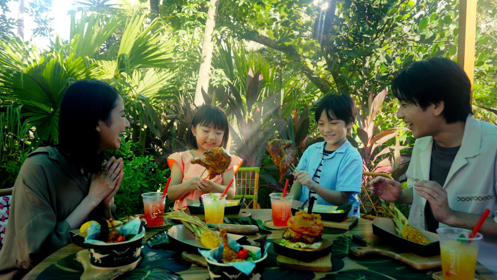 Family enjoying a meal at JUNGLIA OKINAWA Park surrounded by lush greenery.
