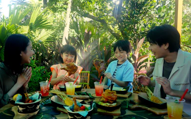 Family enjoying a meal at JUNGLIA OKINAWA Park surrounded by lush greenery.