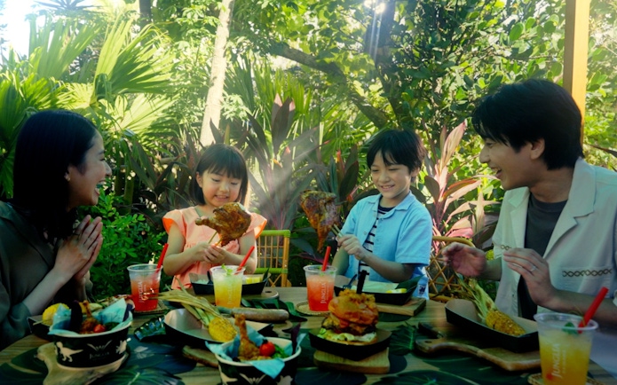 Family enjoying a meal at JUNGLIA OKINAWA Park surrounded by lush greenery.